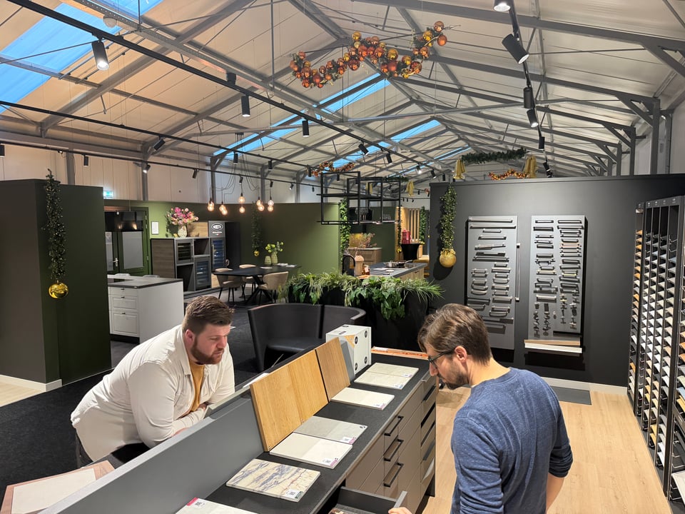 Two men look at different options for kitchen countertops and drawers.