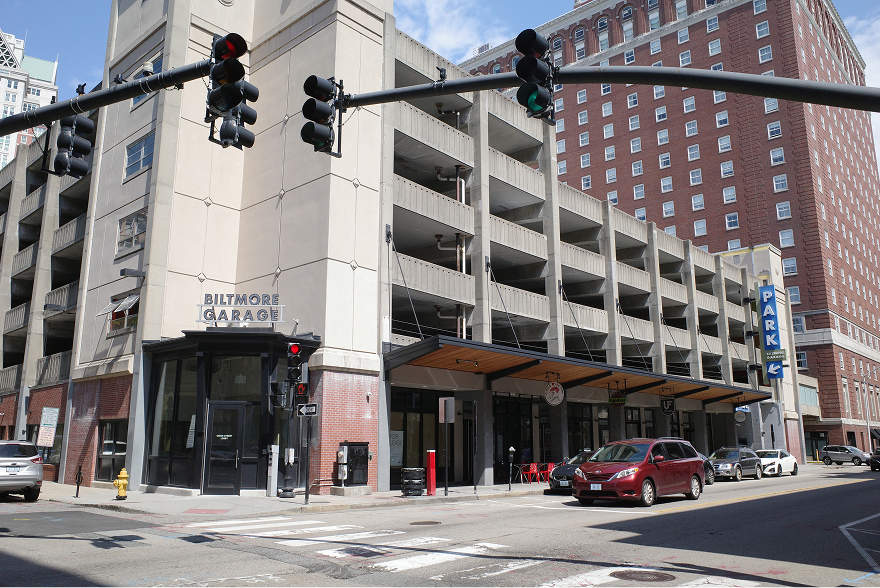 Corner view of the Biltmore Garage showing both the upper parking levels and the row of shops at ground level.