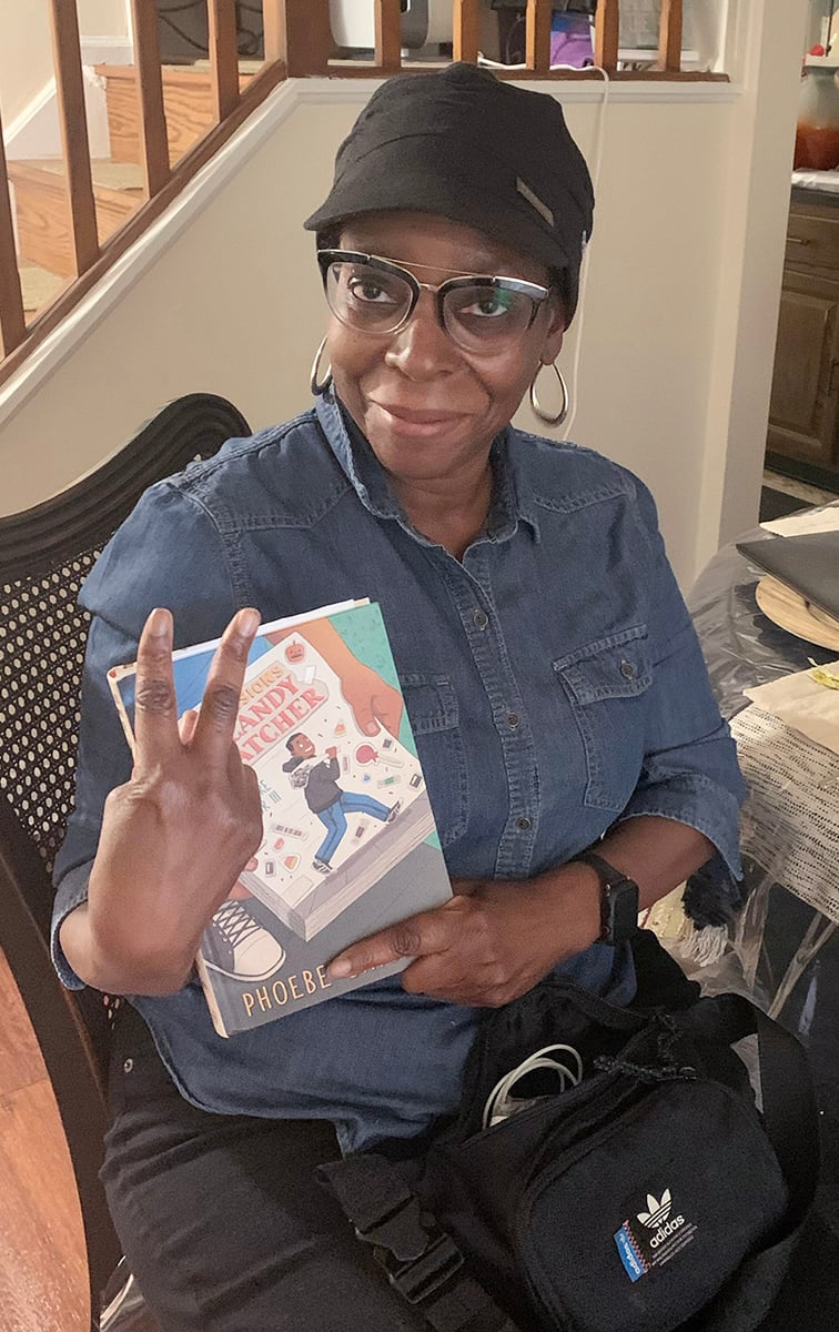 woman holds up a book and makes a peace sign