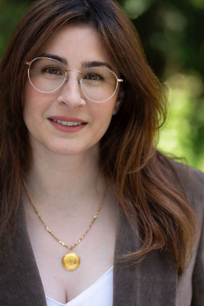 White lady with brown hair and glasses.