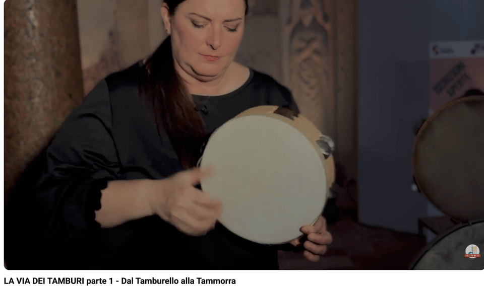 Alt text: A video still of a woman playing a frame drum