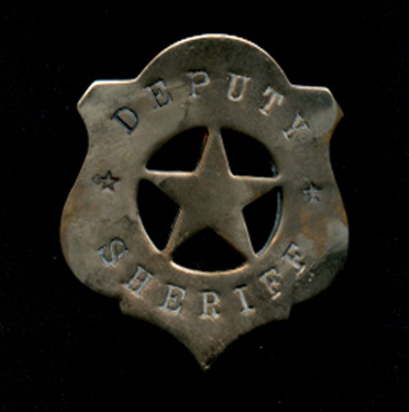 A silver deputy Sheriff's badge with a star in the centre and a black background