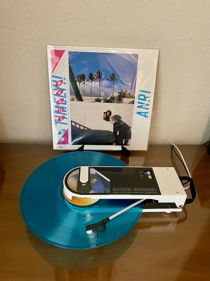 Photo of a small white record player, the Sound Burger, playing a blue LP, Anri's TIMELY