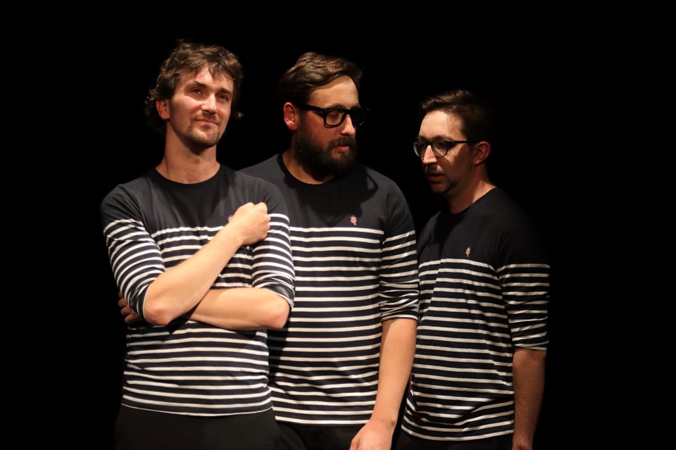 Three performers wearing striped shirts and looking handsomely mysterious.