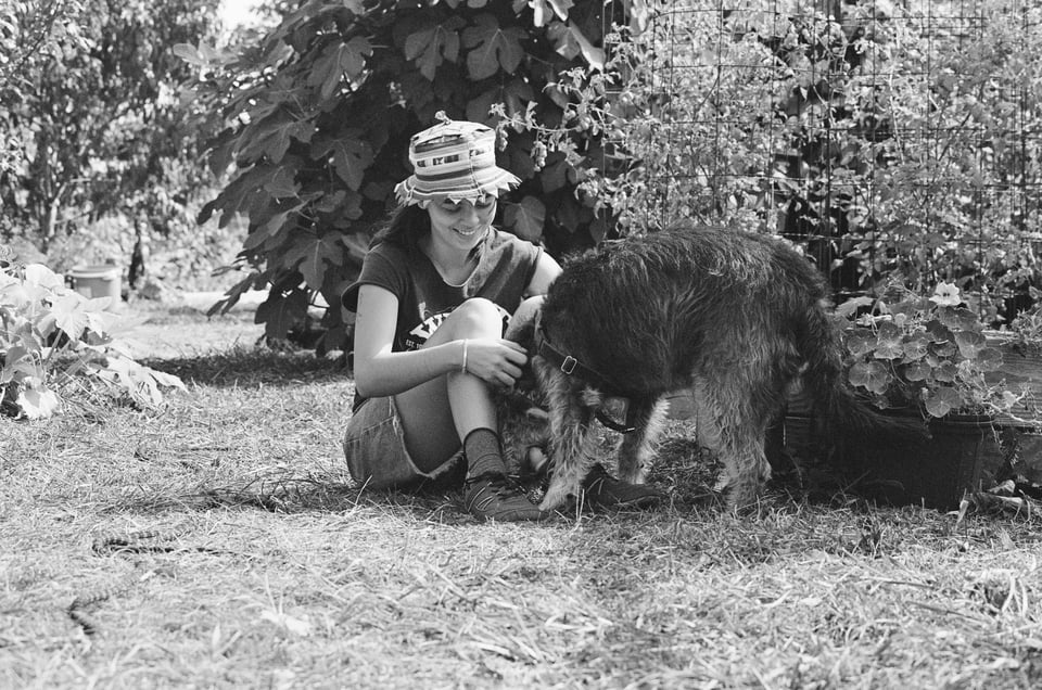 black and white photo of a person playing with a dog in a garden