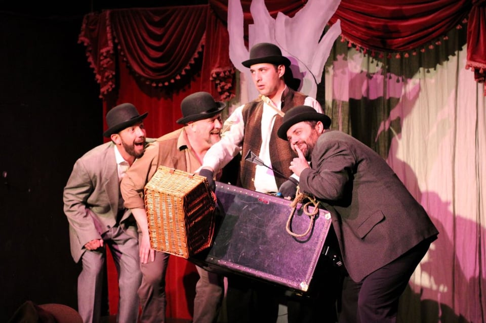 Four men wearing rags and bowler hats looking mischievous