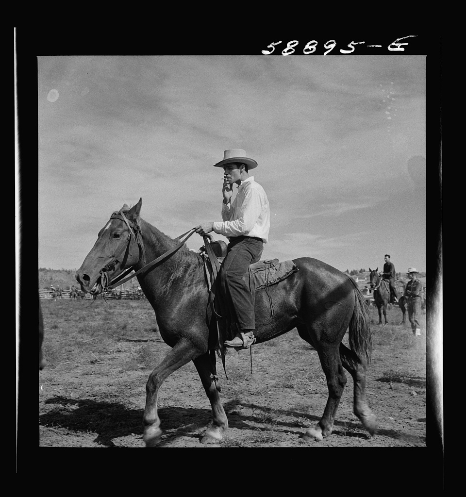 August 1941 nitrite negative, featuring an image of a cowboy sitting on a horse smoking a cigarette in Ashland, Montana by photographer Marion Post Wolcott, from the Library of Congress (public domain image)
