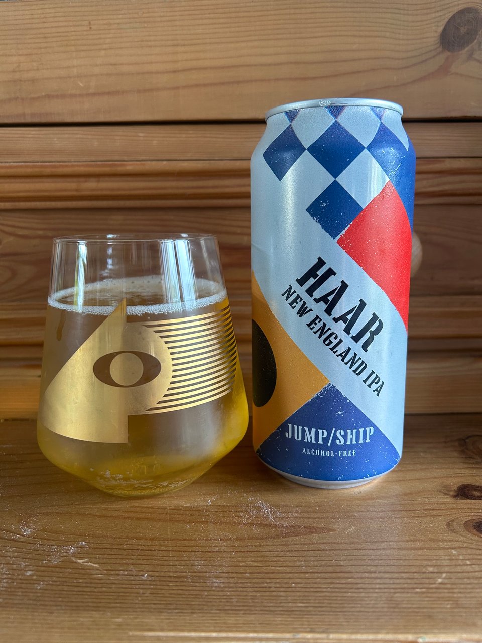A can of Haar alcohol free beer is next to a glass with a gold pattern on it mostly filled with golden liquid. Image by Rowan Ambrose