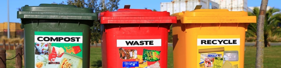 Green, red and yellow waste bins labelled Compost, Waste and Recycle