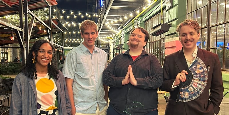 A group of authors smiling outside of a bar.