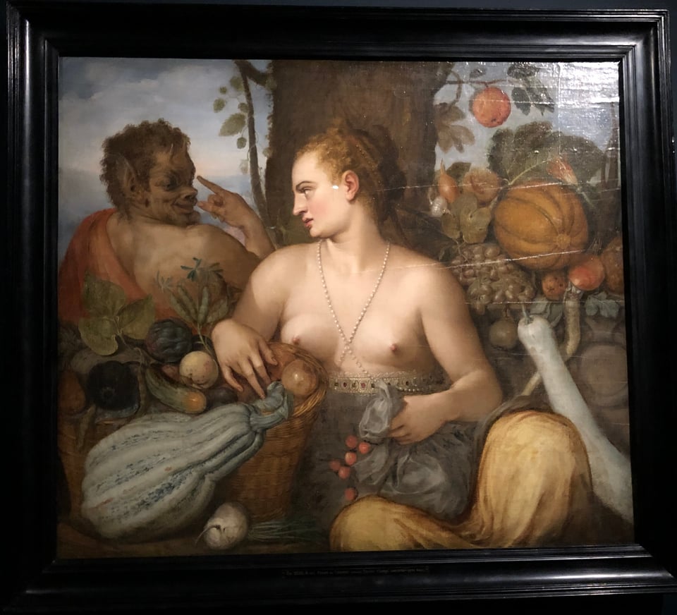 A painting with a young white woman, Pomona in the centre, naked above the waist, wearing flowing robes under neath, surrounded by a fruit and vegetable display, turning over her right shoulder and looking bemused. Turning towards her, facing away from the viewer, is a wild-looking, darker, hairy figure with pointy ears and small horns: Pan. He appears to gesture away from him, as if to suggest that Pomona should leave with him.