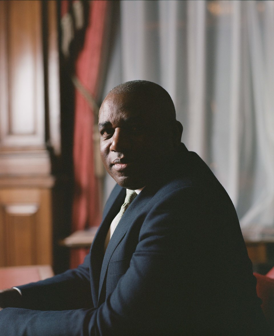 A man sits at a desk backlit from an angle so that half of his face rests in deep shadow