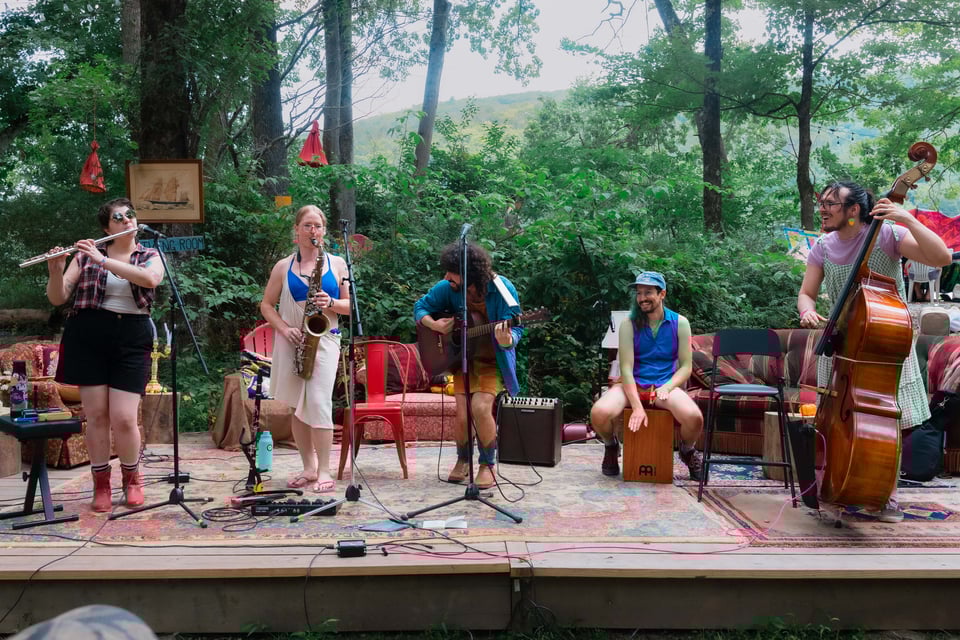 Beche plays on a beautiful stage set up like a living room - Rachel on flute, Betty on sax, Leche on guitar, Dan on cajon, Pat on upright bass