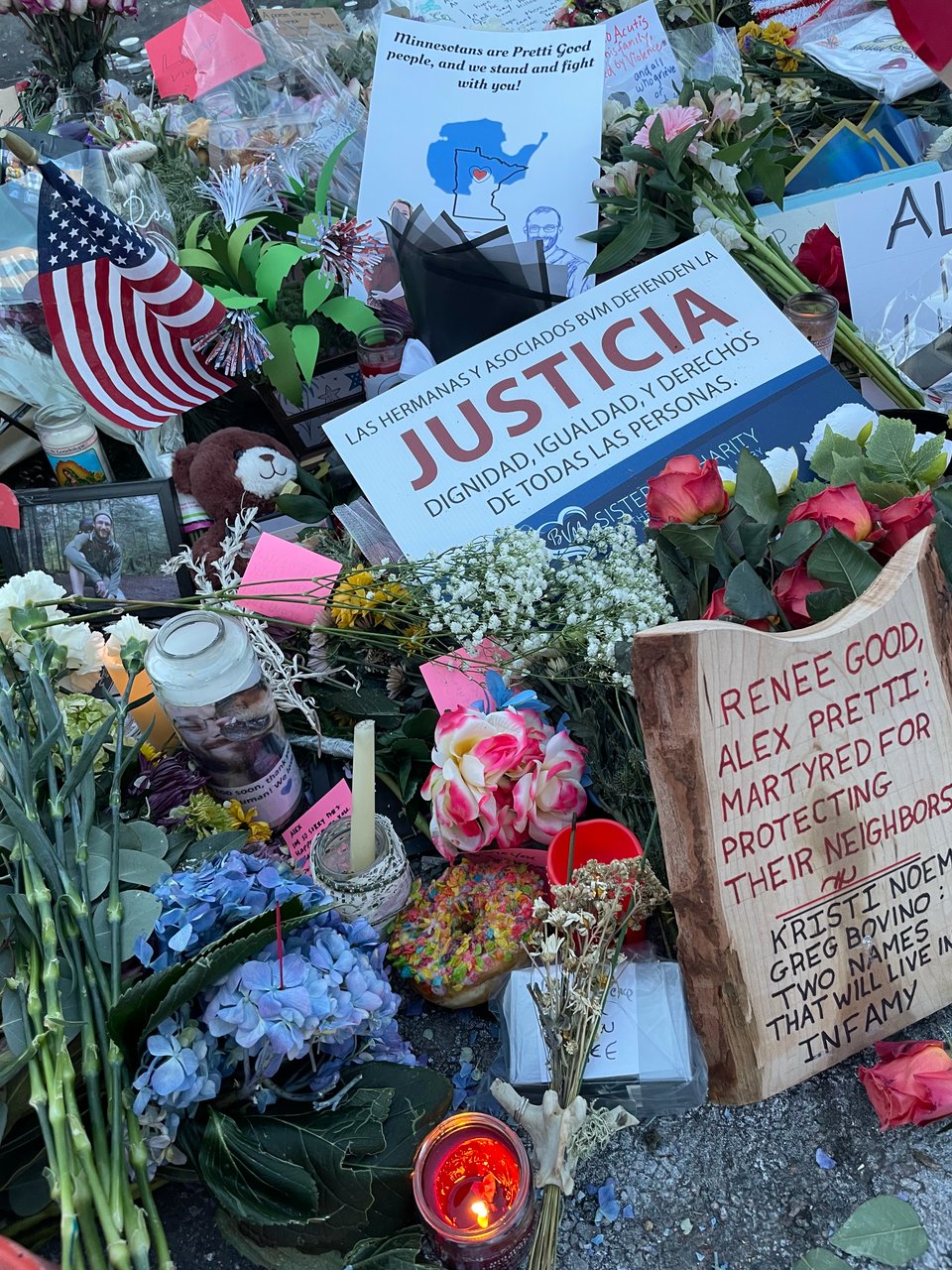 Close-up of flowers, candles, signs and other items left at the site of Alex Pretti's shooting.