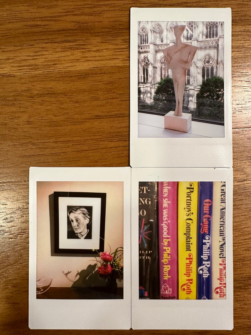3 Instax photos: top right; a human figurine on a windowsill in front of St. Patrick’s Cathedral in NYC; bottom left, a photo of Virginia Woolf with flowers below it; bottom right are the spines of several first edition Philip Roth novels