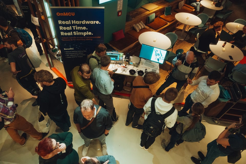 Picture from Munich Embedded 2025 conference, top view down on persons standing in front of and next to a table with a demo from OnMCU