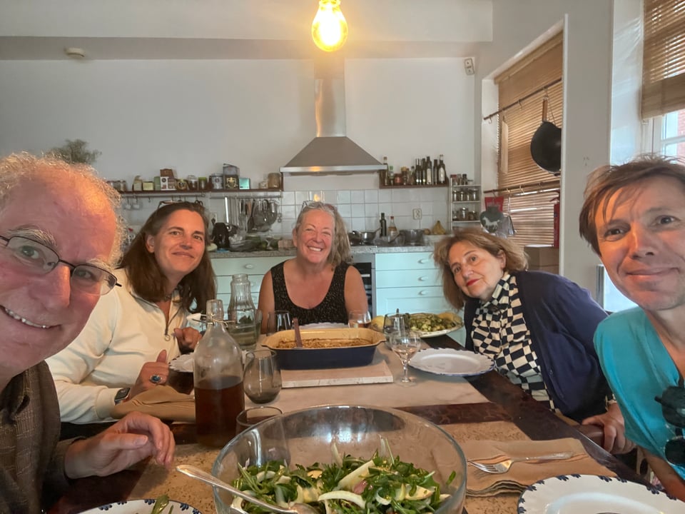 Five people sitting at a dining room table all smiling at the camera.