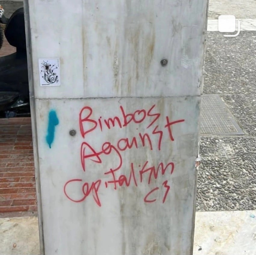Photo of graffiti on a cement (?) column. The graffiti reads "Bimbos Against Capitalism"