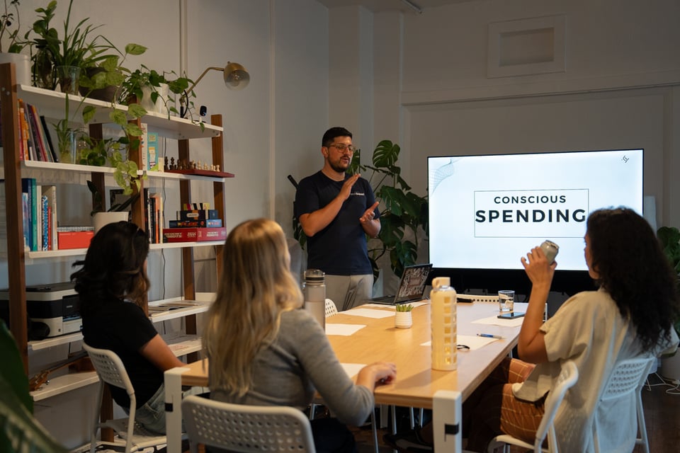 A group of people seated around a table learning from an instructor.