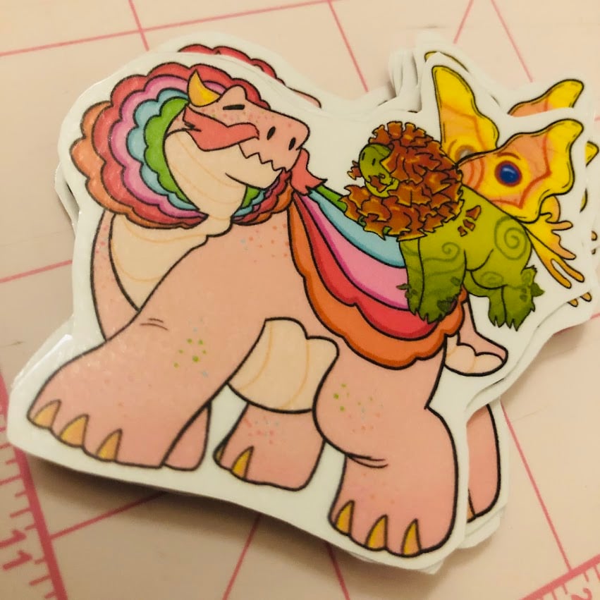 A photo of a sticker featuring two dragons, a large pink dragon and a small green dragon.