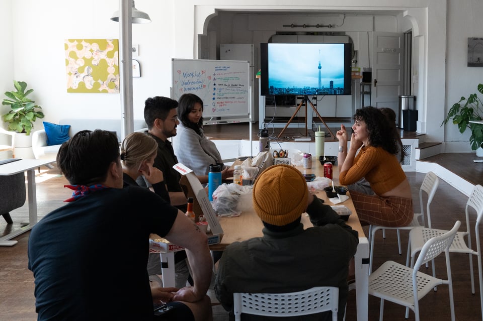 People sitting around a table watching a picture show.