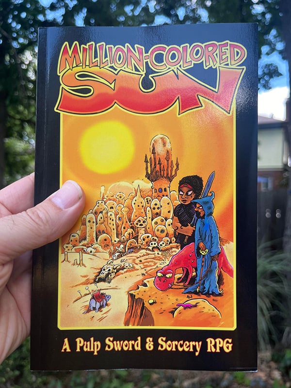 I am holding up a copy of Million-Colored Sun, outdoors.