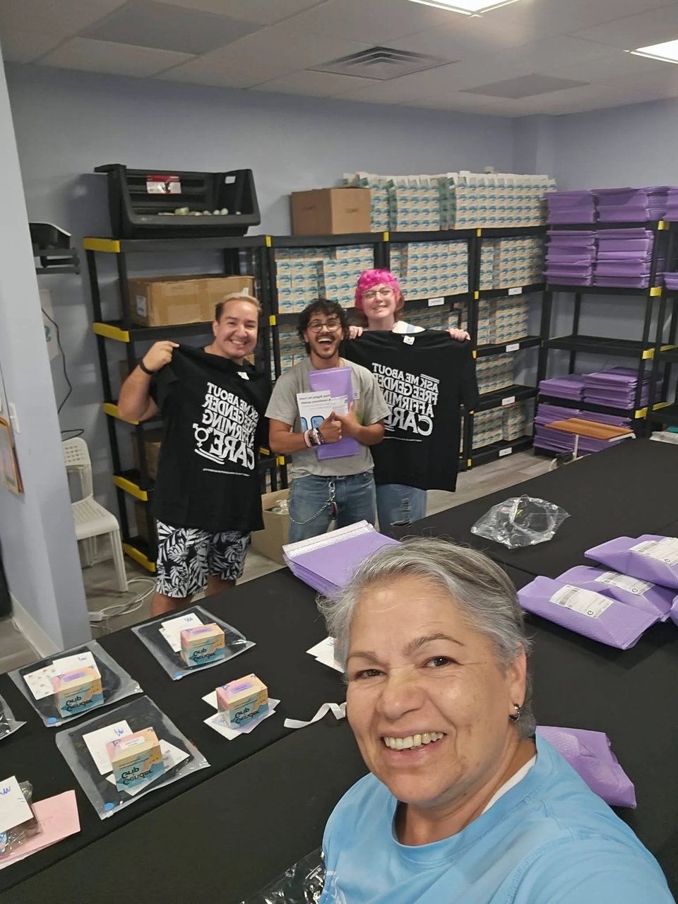 4 people smiling after packing gender affirming care kits