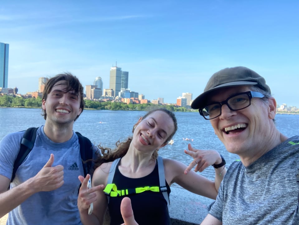 Three people looking windswept but happy, posing by the Charles River