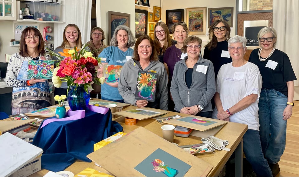 a photo of women smiling and holding up the artworks they created