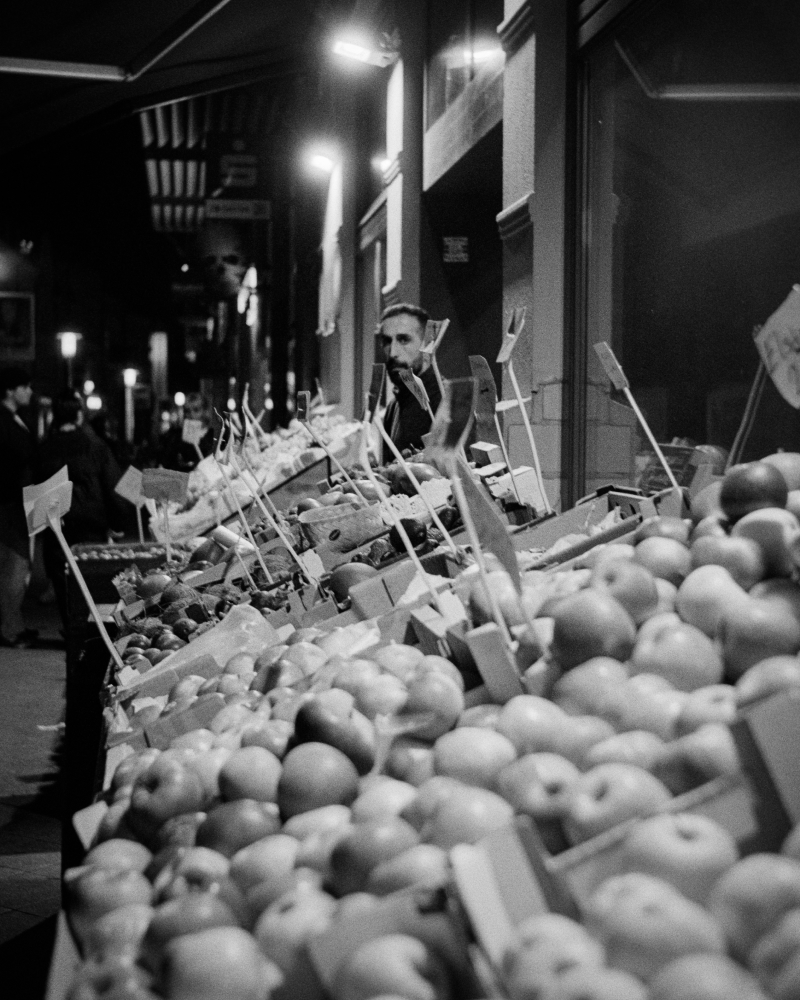 Winter evening vegetable stand with wooden crates of produce displayed in front