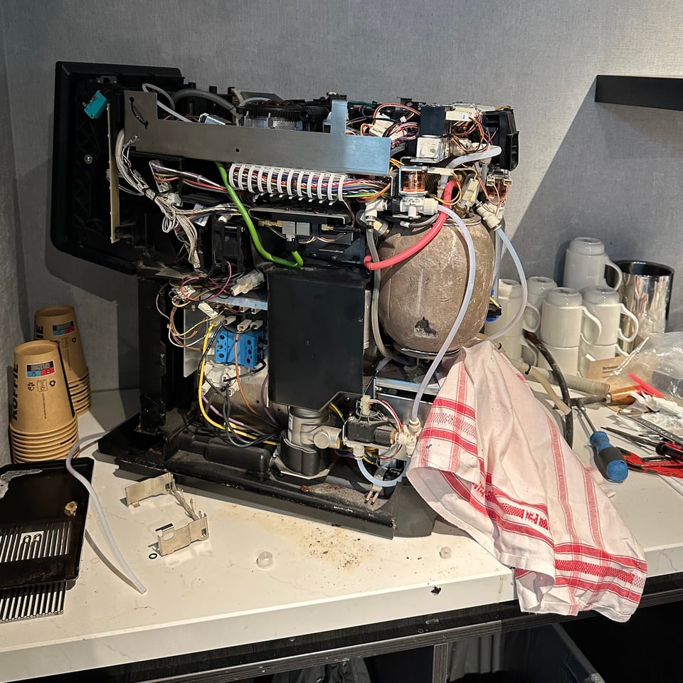 Photo of a coffee machine in a hotel lobby that is being disassembled for repair