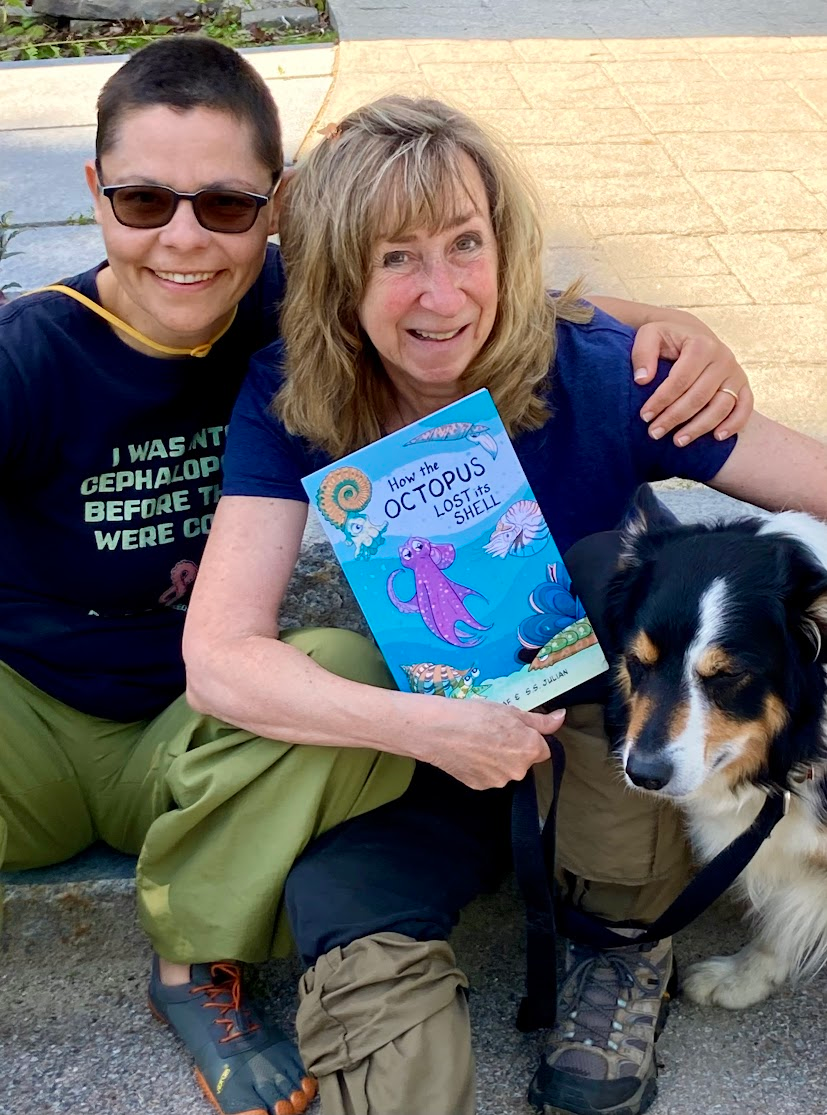 Photo of me (Danna Staaf) and Sy Montgomery and Sy's beautiful collie Thurber, all sitting on the ground. My arm is around Sy's shoulders and she is holding a copy of the zine "How the Octopus Lost Its Shell." She's also wearing an OctoNation shirt (though sadly it's not visible) and I am wearing my "I was into cephalopods before they were cool" t-shirt from "Save the Pacific Northwest Tree Octopus."
