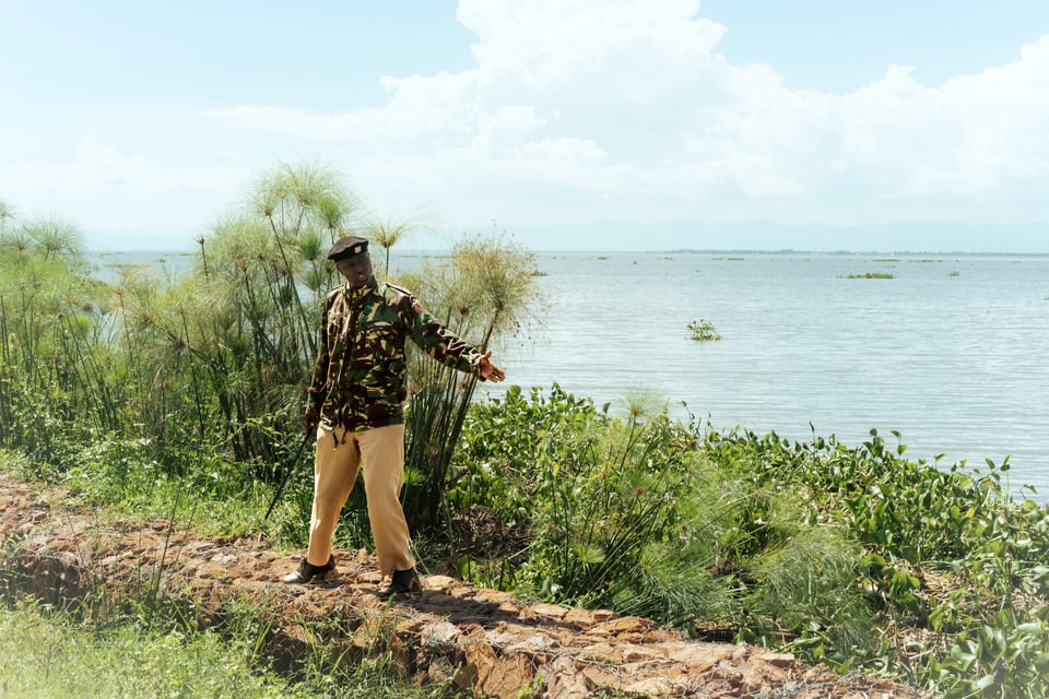 A Kenyan man in military attire gestures to the ground