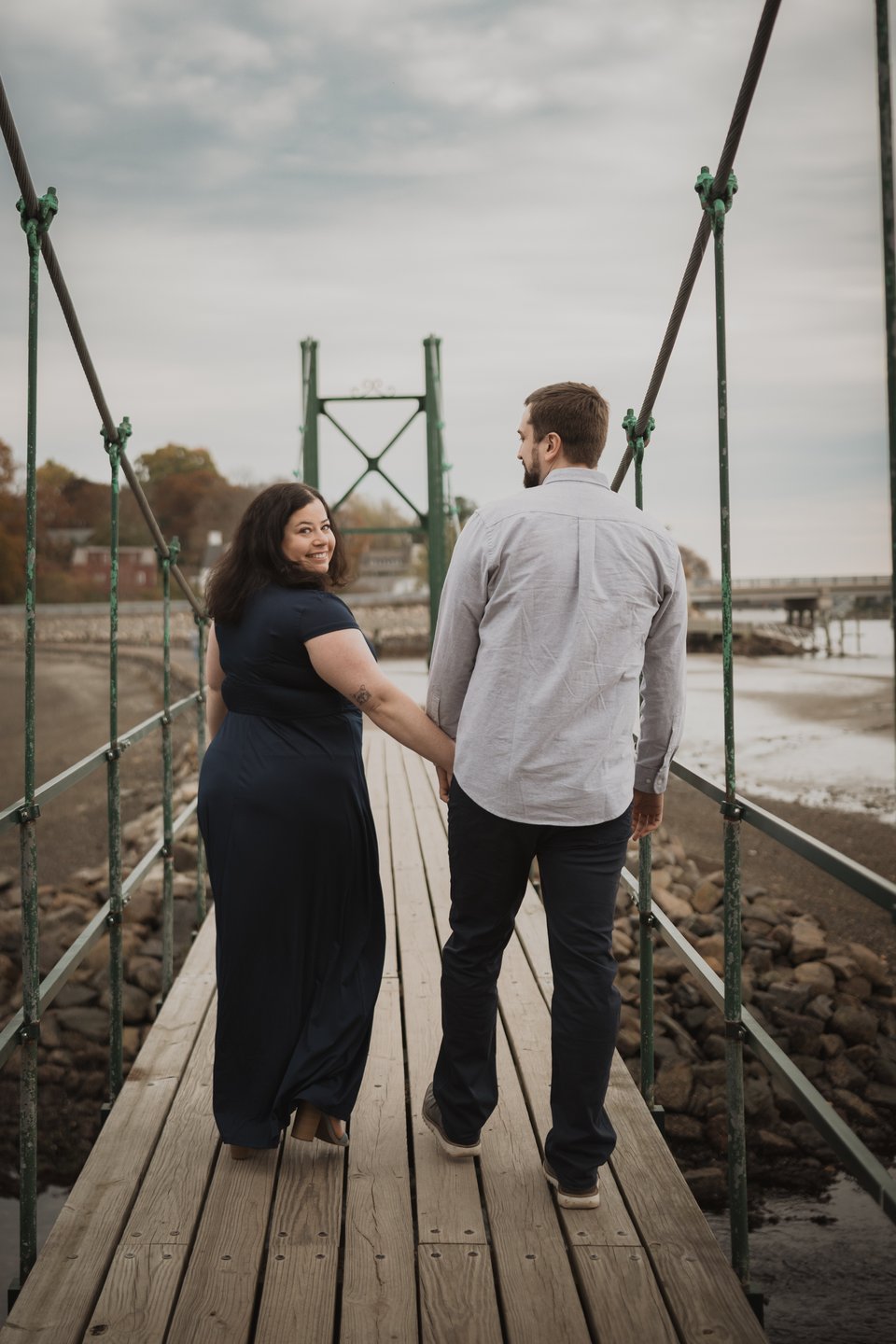 an engaged couple walking on a bridge