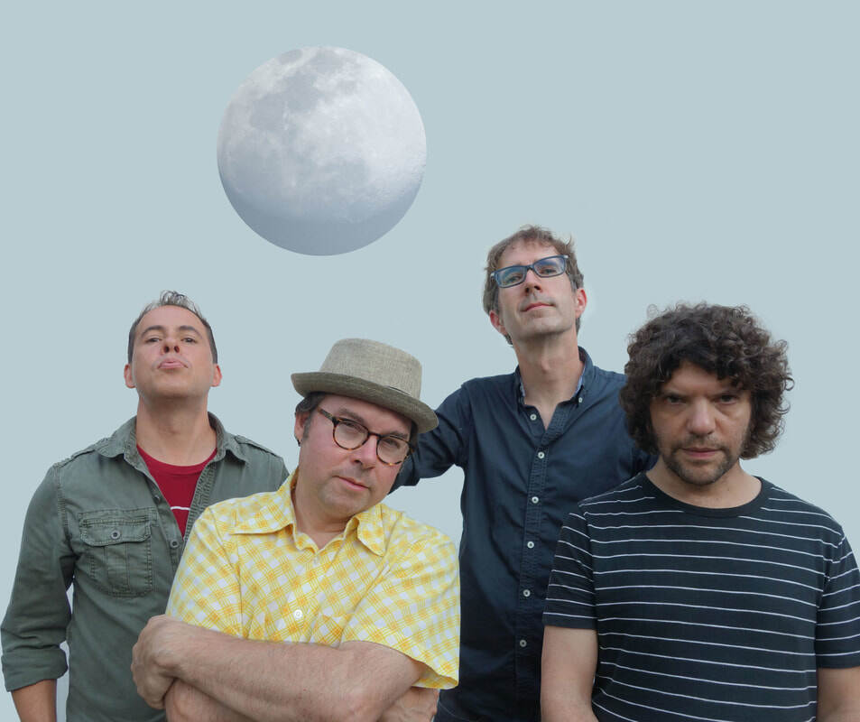 Four men stand in two loose rows of two, with the moon hovering above them.