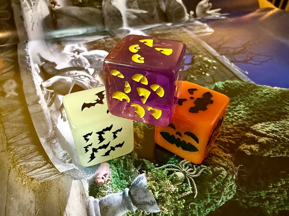 A stack of dice with different colors and patterns, including bats, eyes and pumpkins.