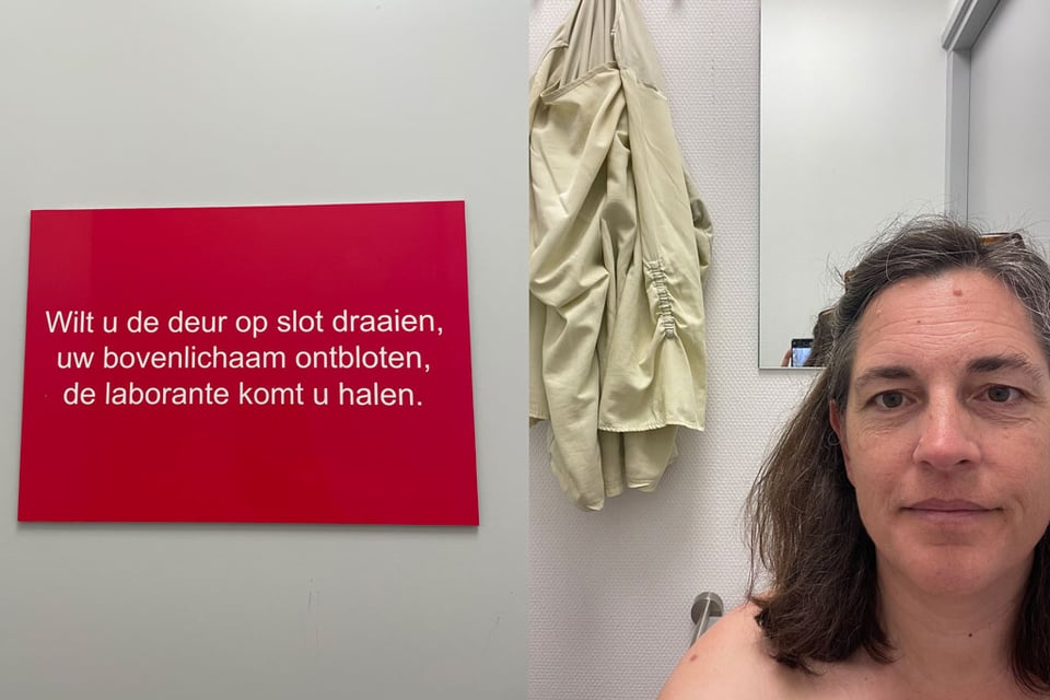 Two photos side by side "Wilt u de deur op slot draaien, uw bovenlichaam ontbloten, de laborante komt u halen." which means "Would you please lock the door, undress your upper body, the lab assistant will come and get you." The photo on the right is a woman facing the camera, her shoulder is bare and her shirt hangs on the hook behind her. She's waiting to be called for her exam.