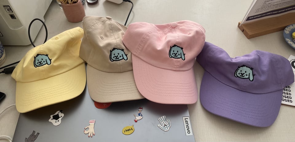 four beautiful hats with an embroidered blue creature on them