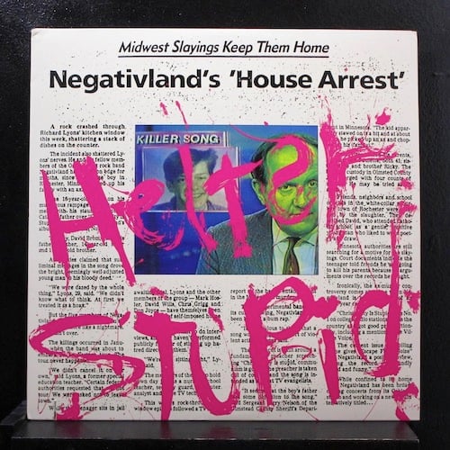 A mockup of a newspaper article. The top reads "Midwest Slayings Keep The Home" then below that "Negativland's 'House Arrest'". Below that is the text of a four column newspaper article, and nestled between is a screengrab of a TV news segment. There is a news reader on the right, a balding white man in a jacket and tie, and behind him is the picture of a smiling white teenager. Above the teenager it says "KILLER SONG." Across all of this, written in pinkish-red and in a way to suggest it was written with a finger dipped in blood, is HELTER STUPID.