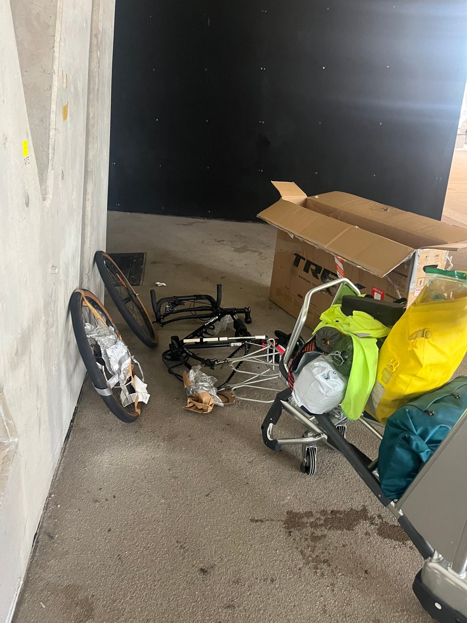 Bike parts littered around a concrete floor with an open bike cardboard box in background.