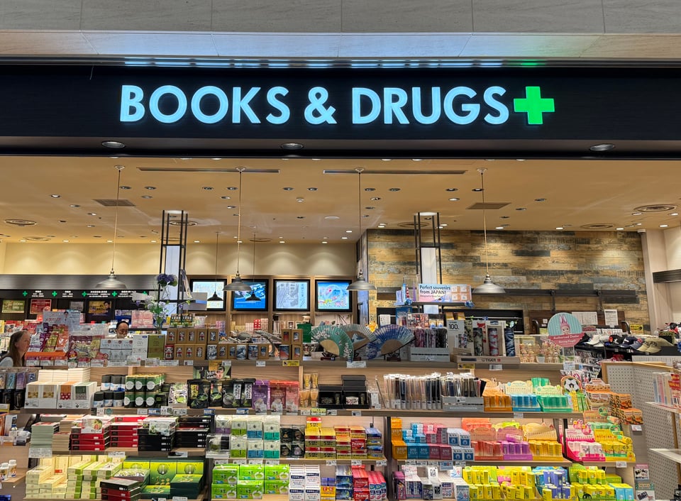 photo of a newsagent in Haneda airport, with a big sign reading BOOKS & DRUGS
