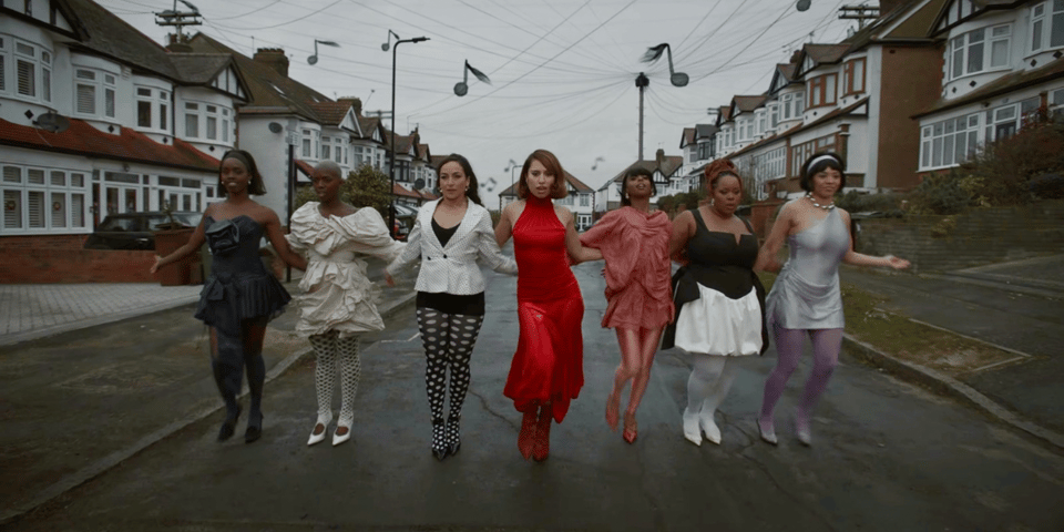 RAYE walks down the street with her friends.