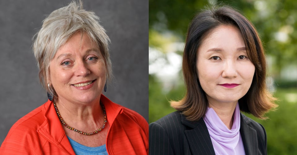 A JMC professor with short gray hair and a red jacket smiles at the camera against a neutral background. Beside her, another JMC professor with shoulder-length dark hair wears a black blazer over a purple scarf, standing outdoors with greenery behind her.