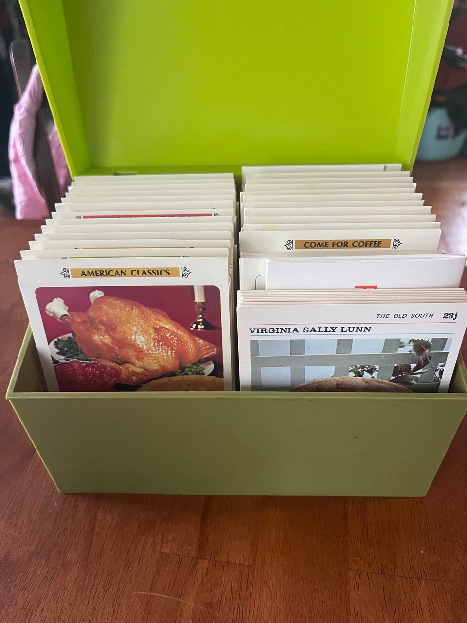 An avocado green plastic box of recipe cards in two rows with labels for different situations that the recipes are called for.