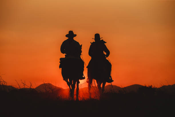 Two cowboys head off into the sunset on horseback