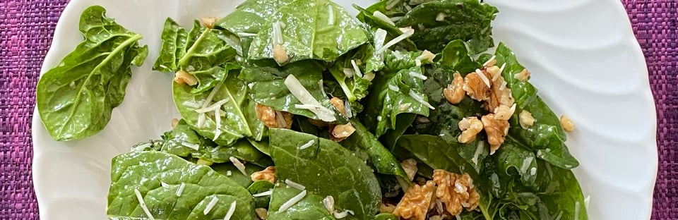 A plate of spinach salad with walnuts, because spinach leaves are rich in folate