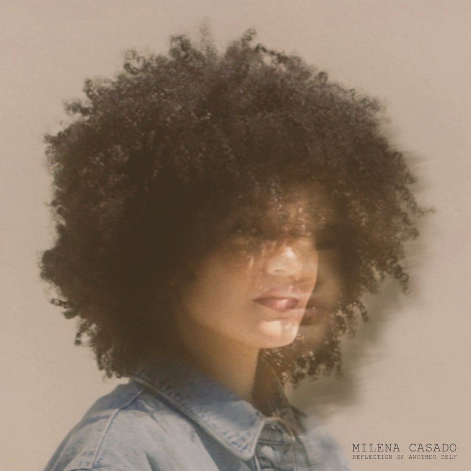 a photo of a black woman with a big afro and a denim, collard shirt staring off into the distance.