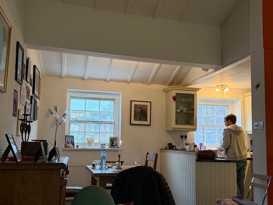 A man stands at the sink in a kitchen washing a water bottle.