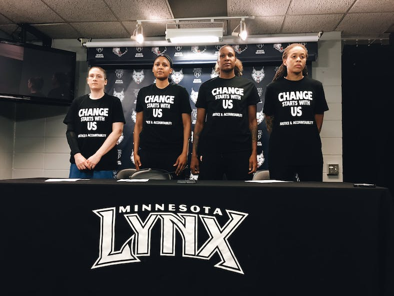 Lynx players standing at a presser with "Change starts with us" shirts