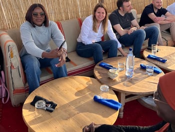 Women sitting at outdoor tables in sunshine, talking.